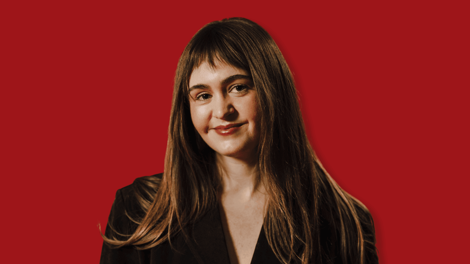 Professional woman standing in front of red background.