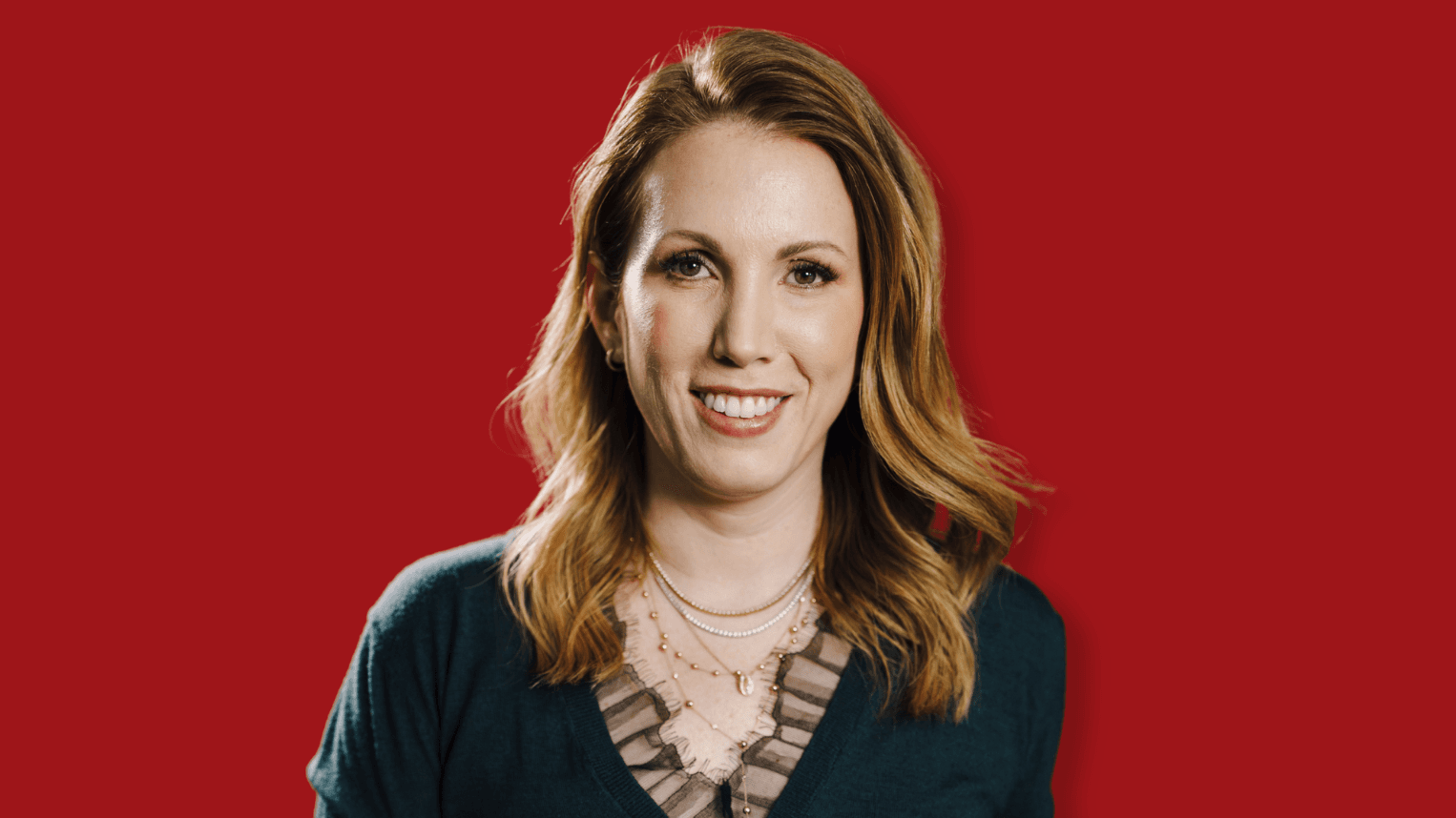 Professional woman standing in front of red background.