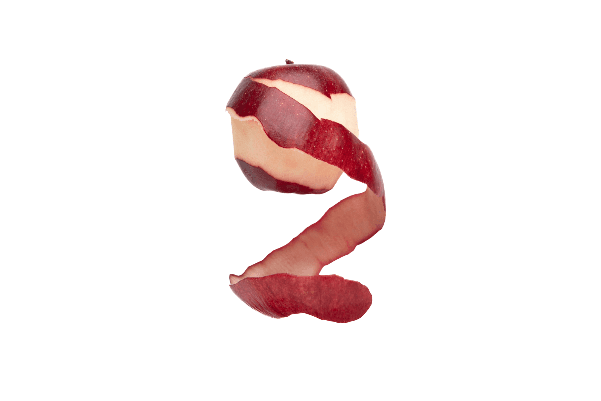 Peeling apple against white backdrop.