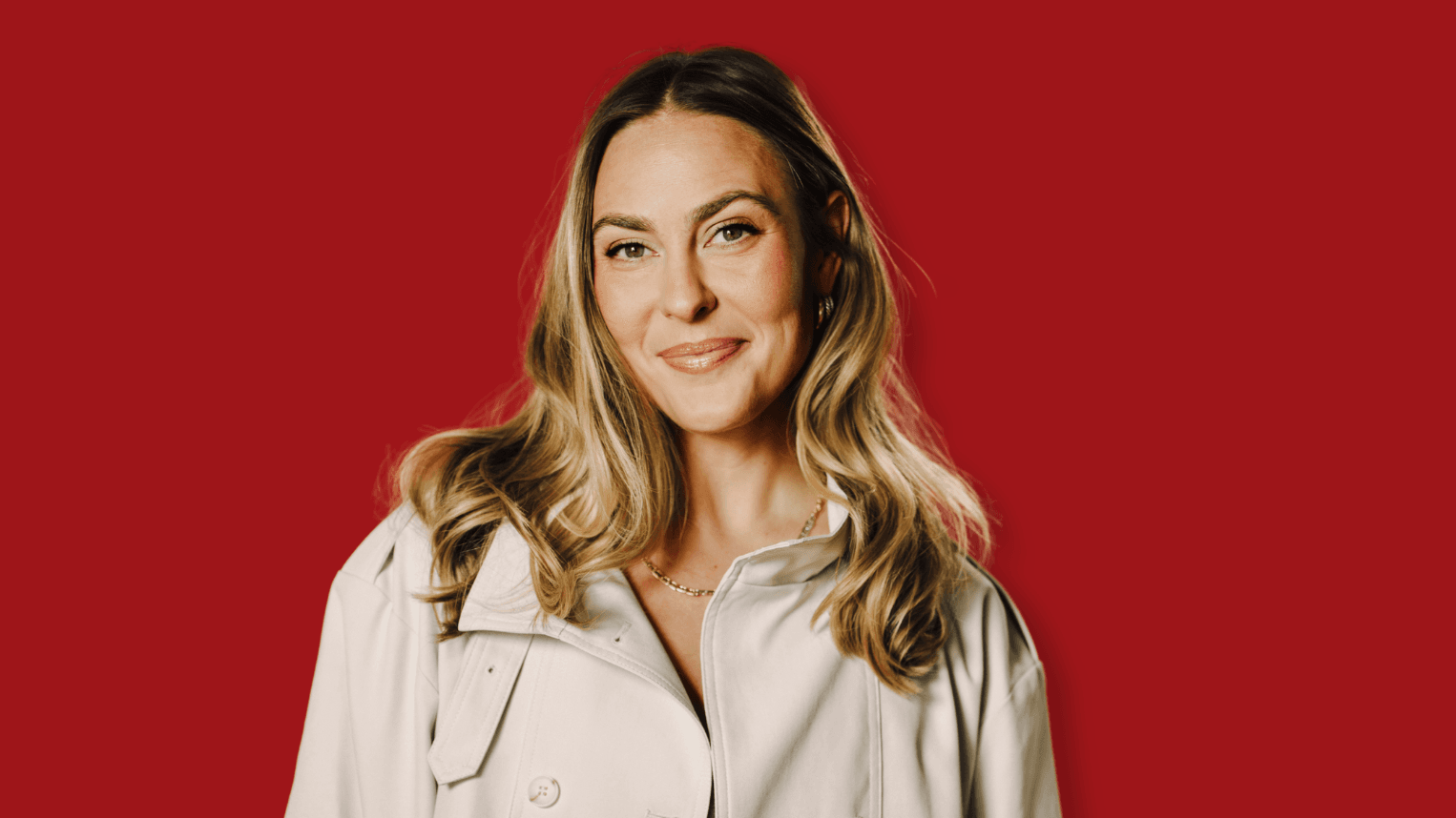 Professional woman standing in front of red background.